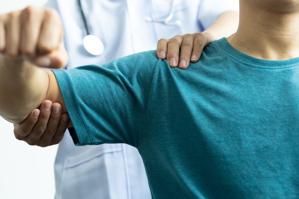 a man in a blue shirt receives physical therapy treatment for his arm - highlighting the different types of physical therapy