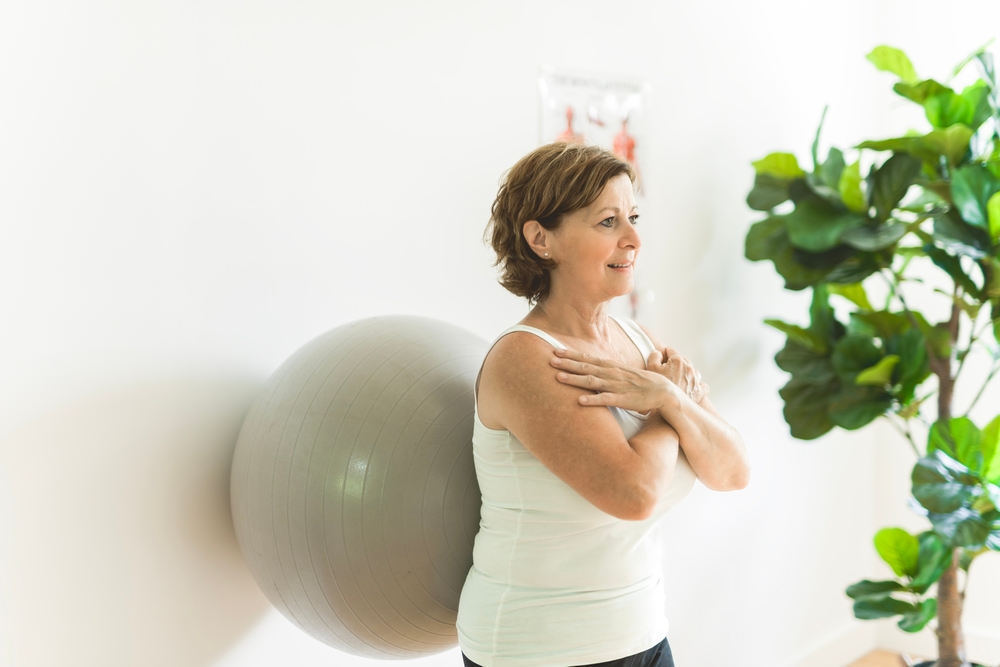 Woman practicing wall sits with an exercise ball for fall prevention physical therapy