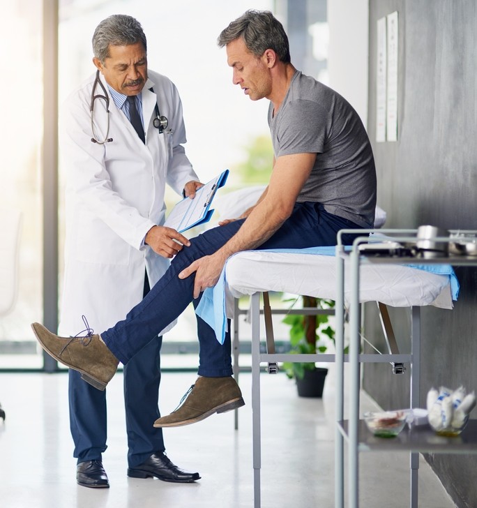 middle aged man recieving PT treatment for his knee sprain or tear