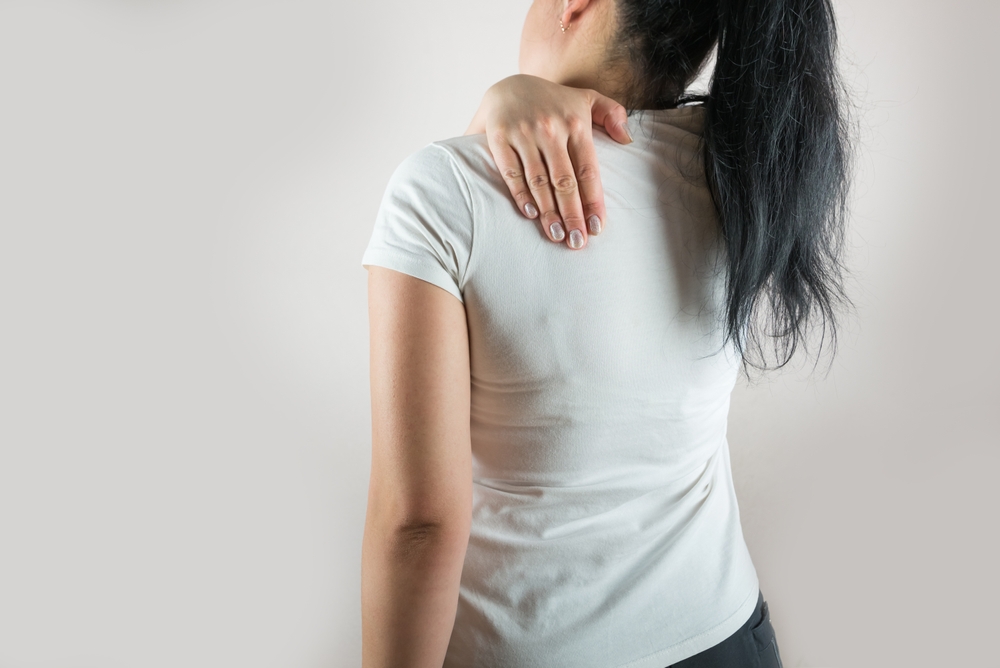 A woman experiencing shoulder blade pain.